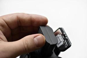 The battery of the SLR camera. Changing the camera battery in close-up. The camera battery is in the photographer's hand. photo