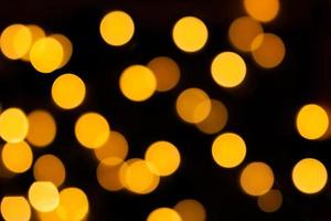 Yellow blurred bokeh on black isolated background. Defocused lights. For overlay design. New Year, Christmas, holiday photo