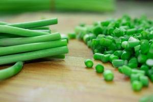 Cutting green garlic on wooden cutting board photo