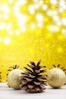 Pine cones with shiny balls on back yellow shiny background with stars. Christmas, New Year. Vertical. Copy space photo