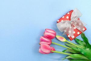 Bouquet of pink tulips with red box with circle and bow on blue background. Holiday, March 8, Birthday, International women's and Mother's day, St. Valentine's. Copy space photo