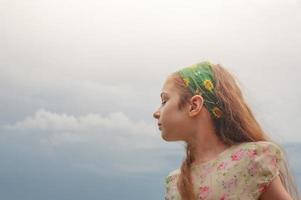 una chica con un vestido en el fondo del cielo. retrato de una adolescente con el pelo largo. foto