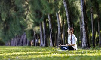 Panorama of woman relaxingly practicing meditation in the pine forest to attain happiness from inner peace wisdom for healthy mind and soul concept