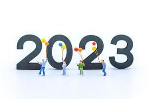 2023 New Year Kid and Family Concept. Closeup of group of children walking and playing with balloon with wooden number on white background. photo