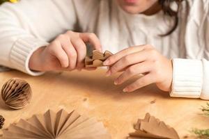 la niña hace decoraciones para árboles de navidad con papel con sus propias manos. instrucción paso a paso foto