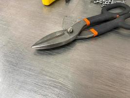 Large iron sharp metal scissors metal cutters lie on an iron table. Hand-held locksmith tools. The background