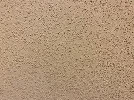 The texture of the beige yellow surface of the plaster-plastered wall with bark beetle type plaster on the wall in the entrance. The background photo