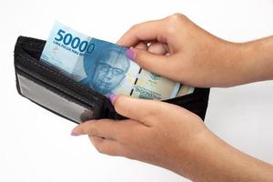 a woman is taking out fifty thousand rupiah from her leather purse photo