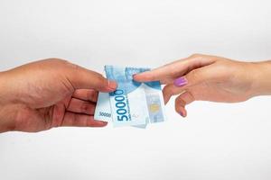 Close up of a woman and a man doing a fifty thousand rupiah money transaction, financial concept, currency concept, buying and selling concept photo