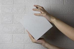 Hands with an empty cardboard box on a light brick wall background photo