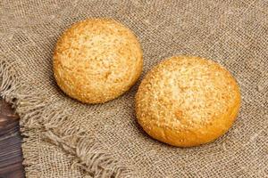 Fresh homemade bread rolls with sesam seeds on wooden table photo