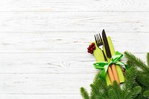 Top view of christmas decorations on wooden background. Fork and knife on napkin tied up with ribbon and empty space for your design. New year pattern concept photo
