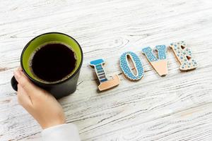 Female hands holding cup of coffee and cookies on wooden table photo