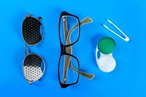un conjunto de accesorios para la vista. concepto médico. gafas estenopeicas, lentes con recipiente y gafas para la vista. vista superior foto