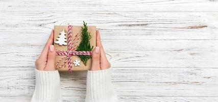 Woman hands give wrapped christmas handmade present in paper top view banner . Copy space photo