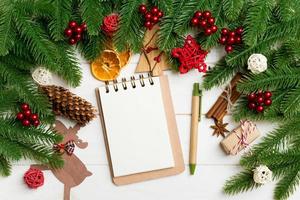 Top view of fir tree branches, notebook and festive decorative toys on wooden background. New Year time concept photo
