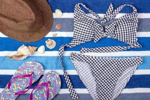 Summer background with straw hat, flip flops and swimsuit. Top view photo