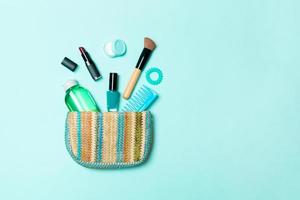 productos de maquillaje que se derraman de la bolsa de cosméticos sobre fondo azul pastel con espacio vacío para su diseño foto