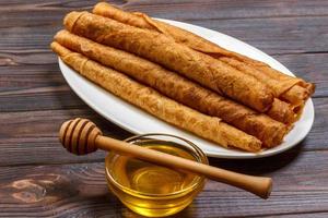 Stack of tasty pancakes with honey in jar on wooden bachground photo