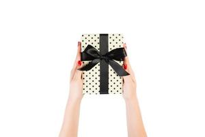 Woman hands give wrapped Christmas or other holiday handmade present in yellow paper with black ribbon. Isolated on white background, top view. thanksgiving Gift box concept photo