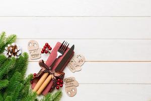 Top view of christmas decorations on wooden background. Fork and knife on napkin tied up with ribbon and empty space for your design. New year pattern concept photo