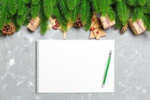 Top view of a notebook on cement holiday background made of fir tree and New Year decorations. Christmas time concept photo