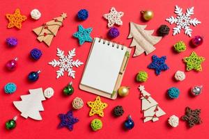 Top view of notebook on red background made of holiday decorations and toys. Christmas ornament concept photo