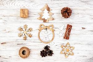 Christmas composition. Gift, christmas decoration, snowflake, pine cones on rustic vintage wooden background. Flat lay top view photo