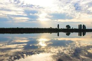 puesta de sol con nubes, rayos de luz sobre el río con reflejos foto