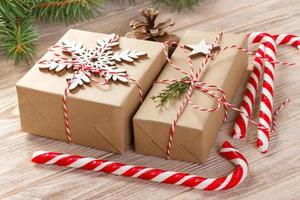 rama de abeto con caja de regalo de navidad y bastones de caramelo sobre fondo de madera con espacio de copia foto