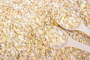 Oatmeal with a wooden spoon background, oat flakes background photo