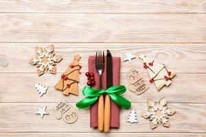 Top view of fork and knife tied up with ribbon on napkin on wooden background. Christmas decorations and New Year tree. Happy holiday concept with empty space for your design photo