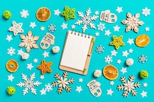 Top view of notebook on blue background with New Year toys and decorations. Christmas time concept photo