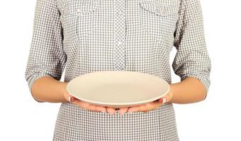 woman holds an empty matte round plate in two hands in front of her. perspective view Template for your design. Isolated on white background photo