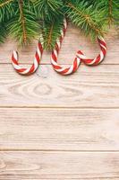 Christmas tree branch and candy cane on a wooden table or board for background. New year theme. Space for text. Toned photo