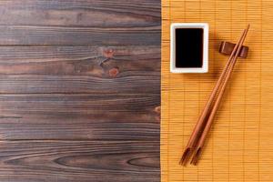 Bamboo mat and soy sauce with sushi chopsticks on wooden table. Top view with copy space background for sushi. Flat lay photo