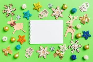 Top view of notebook on green background with New Year toys and decorations. Christmas time concept photo