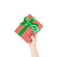 Woman hands give wrapped Christmas or other holiday handmade present in red paper with Green ribbon. Isolated on white background, top view. thanksgiving Gift box concept photo