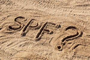 Sun protect factor concept. SPF word written on the beach with question mark photo