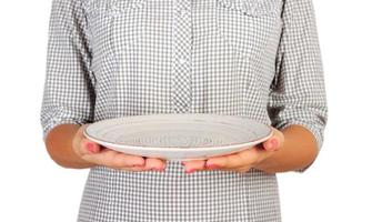 la chica de la camisa a cuadros sostiene un plato blanco redondo vacío frente a ella. mano de mujer sostenga el plato vacío para su diseño. vista en perspectiva, aislada sobre fondo blanco foto