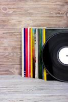 imagen de estilo retro de una colección de viejos discos de vinilo lp con mangas sobre un fondo de madera. copie el espacio foto