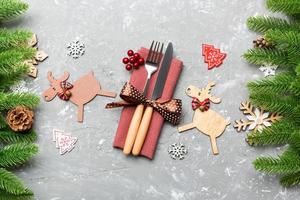 Top view of flatware tied up with ribbon on napkin on cement background. Close up of christmas decorations and reindeer. New Year holiday concept photo