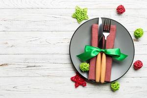 Holiday composition of Christmas dinner on wooden background. Top view of plate, utensil and festive decorations. New Year Advent concept with copy space photo