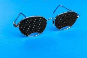 zapatillas de deporte de gafas. gafas de agujero de alfiler negro sobre fondo azul. concepto médico. vista superior foto