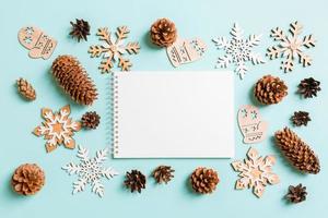 Top view of notebook, holiday toys and decorations on blue Christmas background. New Year time concept photo