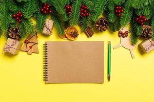 Top view of notebook on yellow background made of Christmas decorations. New Year time concept photo