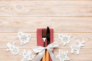 Top view of New Year dinner on wooden background. Festive cutlery on napkin with christmas decorations and toys. Family holiday concept with copy space photo
