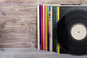 Retro styled image of a collection of old vinyl record lp's with sleeves on a wooden background. Copy space. photo