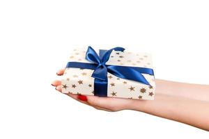las manos de las mujeres dan Navidad envuelta u otro regalo hecho a mano en papel dorado con cinta azul. aislado sobre fondo blanco, vista superior. concepto de caja de regalo de acción de gracias