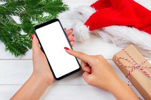 Female buyer makes order at screen of smartphone with copy space. Winter holidays sales. Christmas online shopping photo